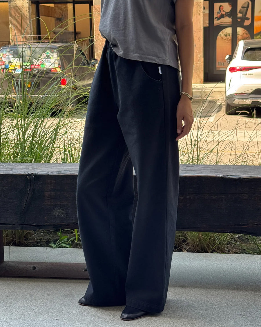 side view of model wearing black relaxed fit cotton canvas pants with side pockets