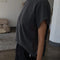 side view of model wearing washed black tee with slight cap sleeves and shorter length