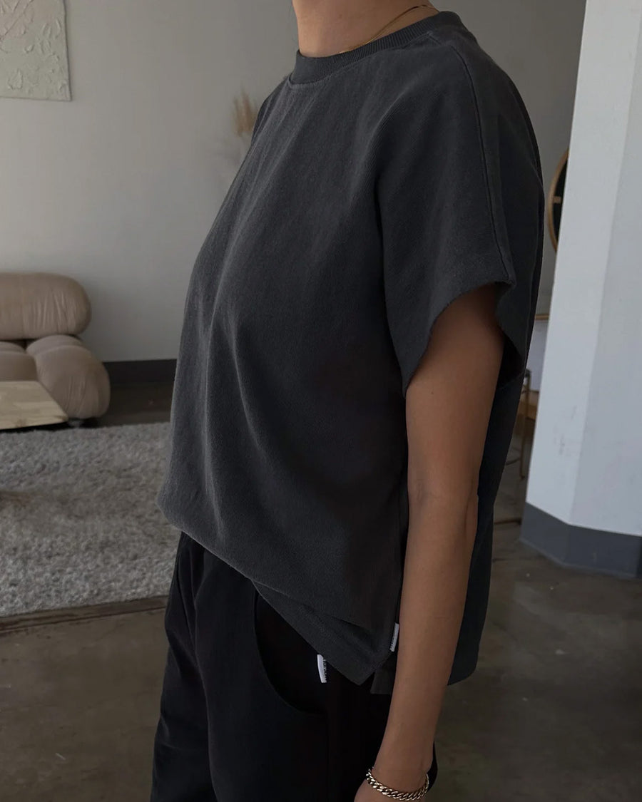 side view of model wearing washed black tee with slight cap sleeves and shorter length