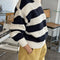 side view of model wearing navy and white thick stripe sweater with mock neckline with yellow bottoms