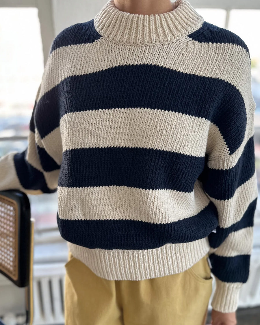 model wearing navy and white thick stripe sweater with mock neckline