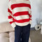 model wearing red and white thick stripe sweater with mock neckline with denim bottoms