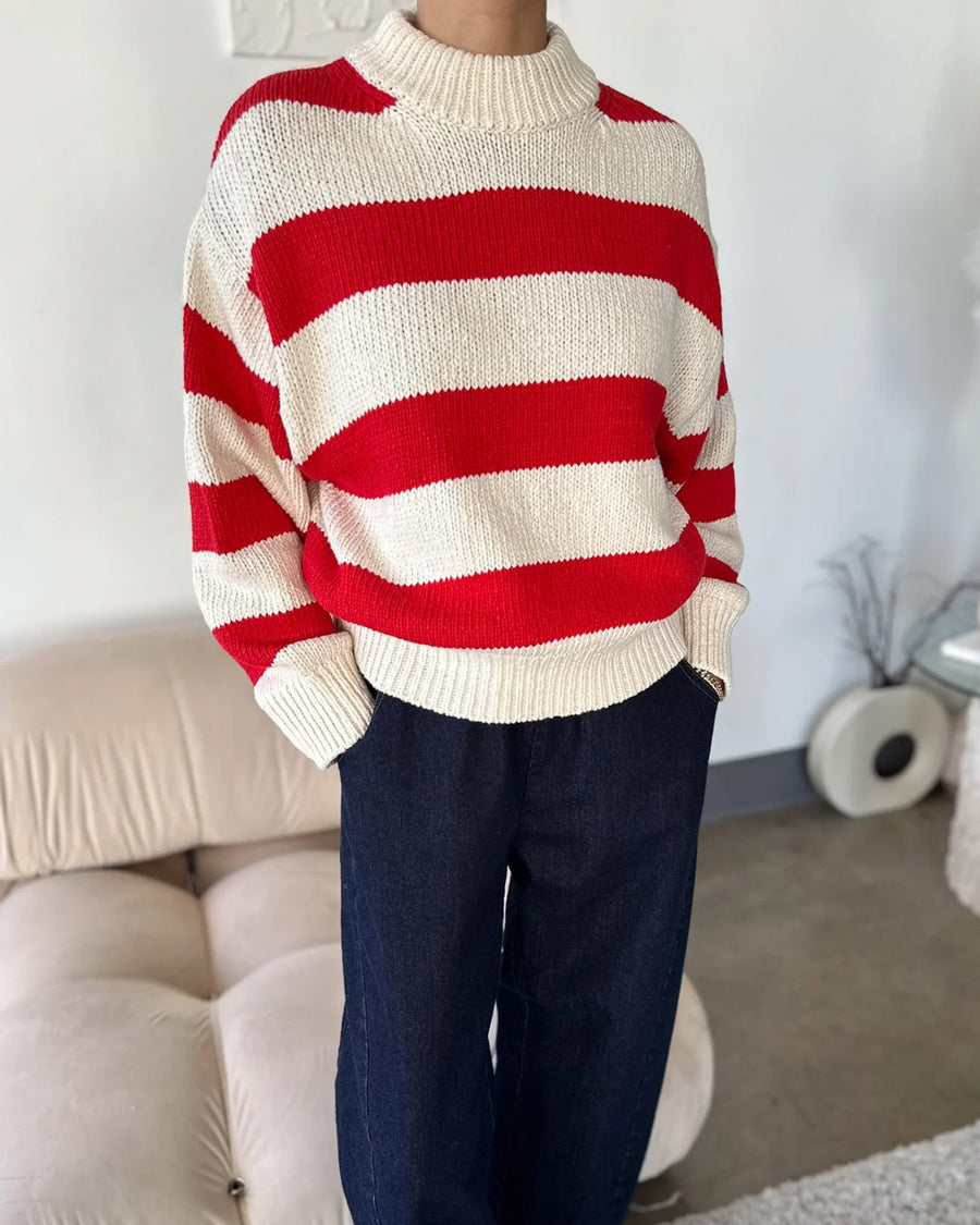 model wearing red and white thick stripe sweater with mock neckline with denim bottoms