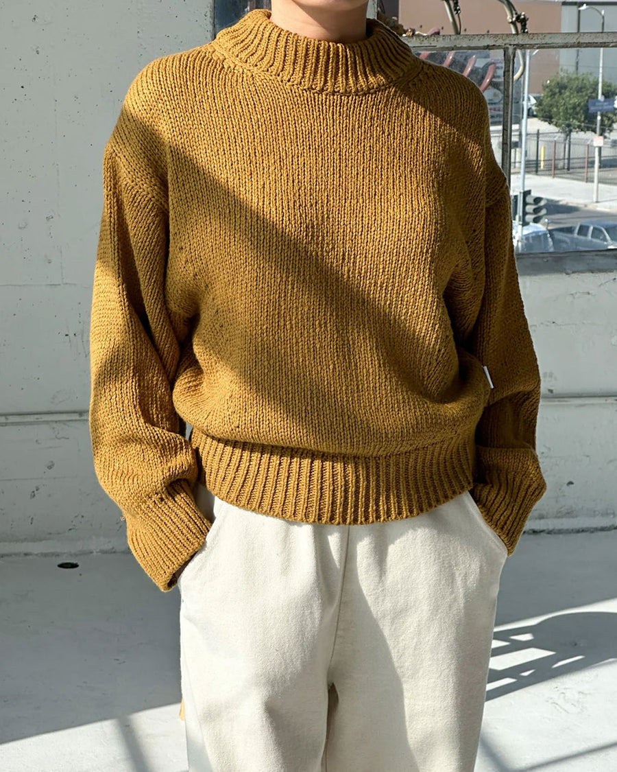 model wearing mustard yellow cotton sweater with thick banded bottom and mockneck