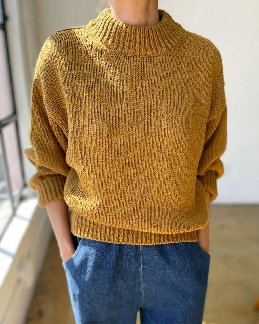 model wearing mustard yellow cotton sweater with thick banded bottom and mockneck