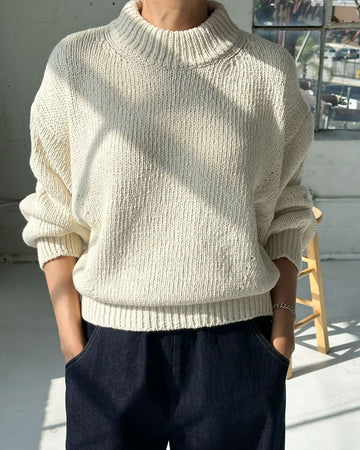 model wearing cream cotton sweater with thick banded bottom and mockneck