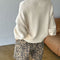 back view of model wearing cream cotton sweater with thick banded bottom and mockneck