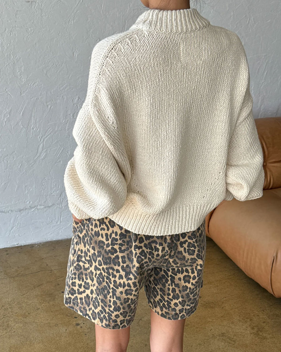 back view of model wearing cream cotton sweater with thick banded bottom and mockneck