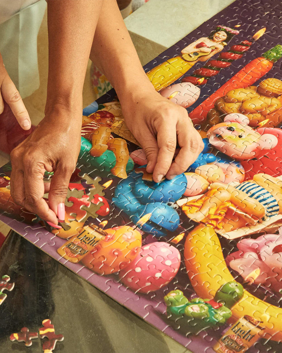 up close of models putting together le puzz 500 piece puzzle with various novelty lit candles