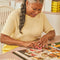 model putting together boxed le puzz 500 piece puzzle with various 'fake foods' being poured