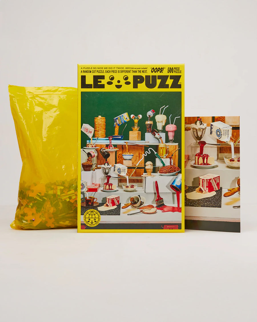 le puzz 500 piece puzzle with various 'fake foods' being poured with box, poster, and bag of puzzle pieces