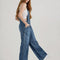 side view of model wearing medium denim overalls with front pocket and lee tag