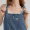 up close of model wearing medium denim overalls with front pocket and lee tag