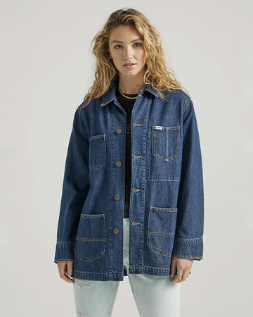 model wearing medium denim chore coat with four front patch pockets and button front