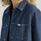 up close of model wearing medium denim chore coat with four front patch pockets and button front