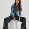 model sitting on white block while wearing black denim a-line trouser