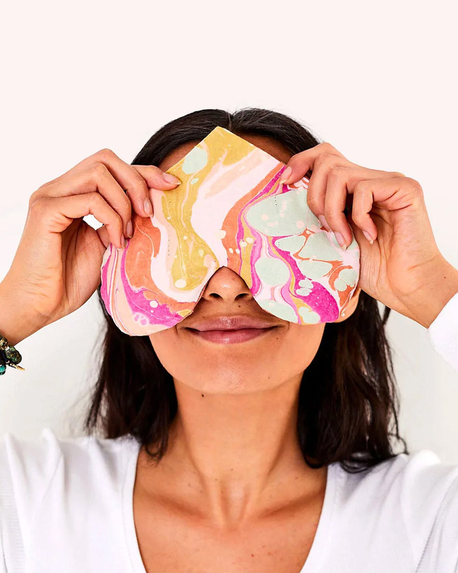 model holding colorful swirl heart shaped eye pillow over their eyes