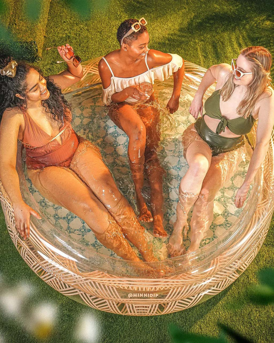 top view of model relaxing in clear inflatable pool with rattan colored lines and scalloped top