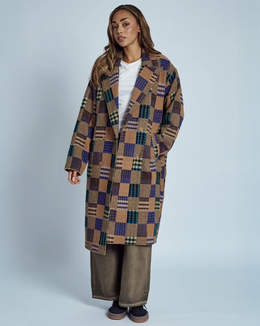 model wearing brown mid length coat with front lapel, button front and colorful checkered patches