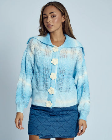 model wearing blue and white knit cardigan with crochet white flower button front and wide lapel collar