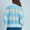 back view of model wearing blue and white knit cardigan with crochet white flower button front and wide lapel collar