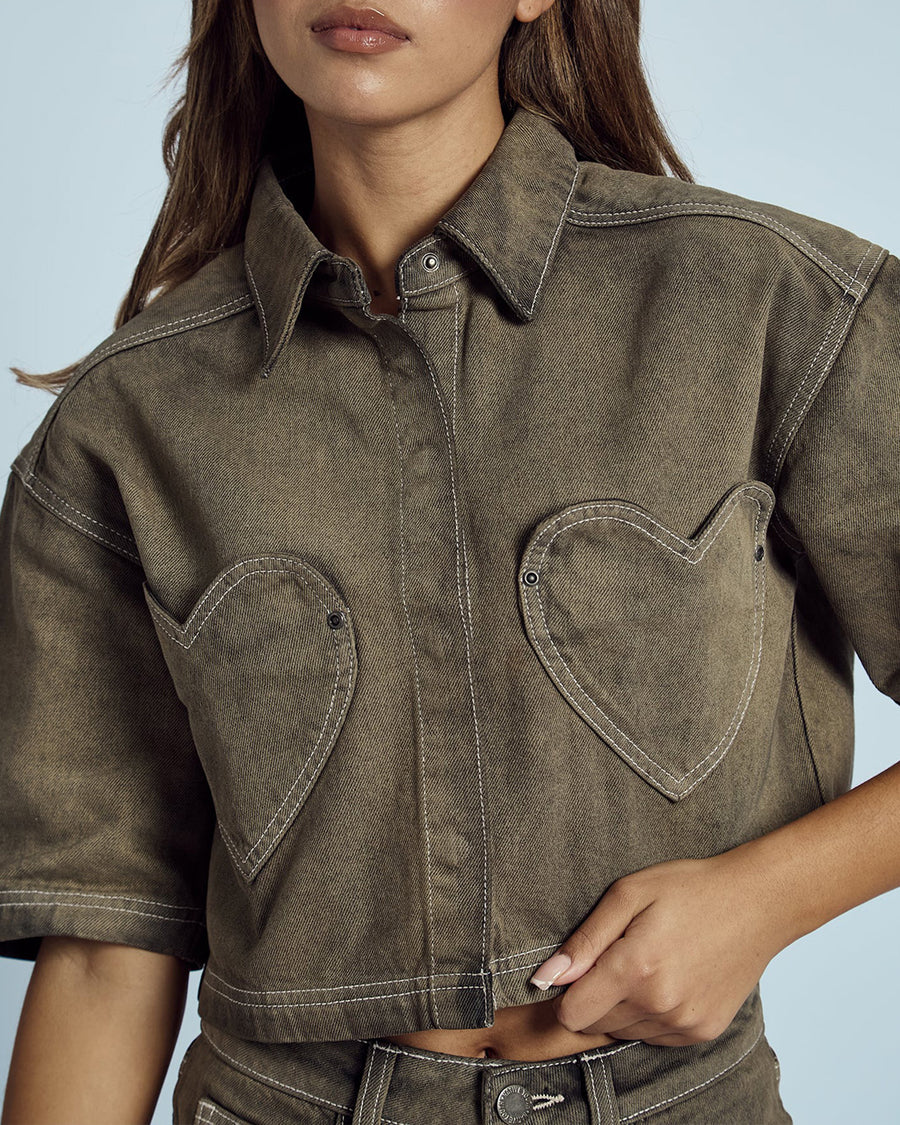 up close of model wearing cropped chocolate acid wash button down top with heart shaped front pockets