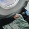 model wearing sage weighted body blanket on their lap on a plane