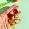 model holding pair of bell pepper earrings in red, orange and yellow tiered