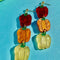 up close of pair of bell pepper earrings in red, orange and yellow tiered