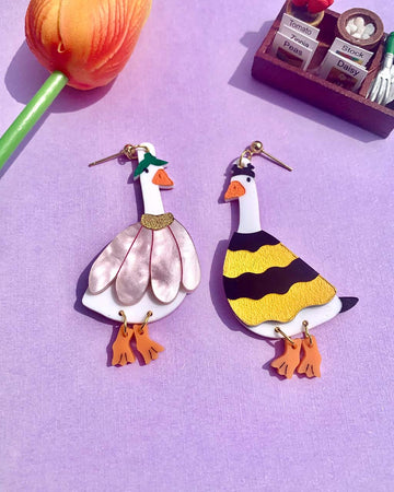 pair of two mismatched duck earrings: goose in a flower costume and goose in a bee costume