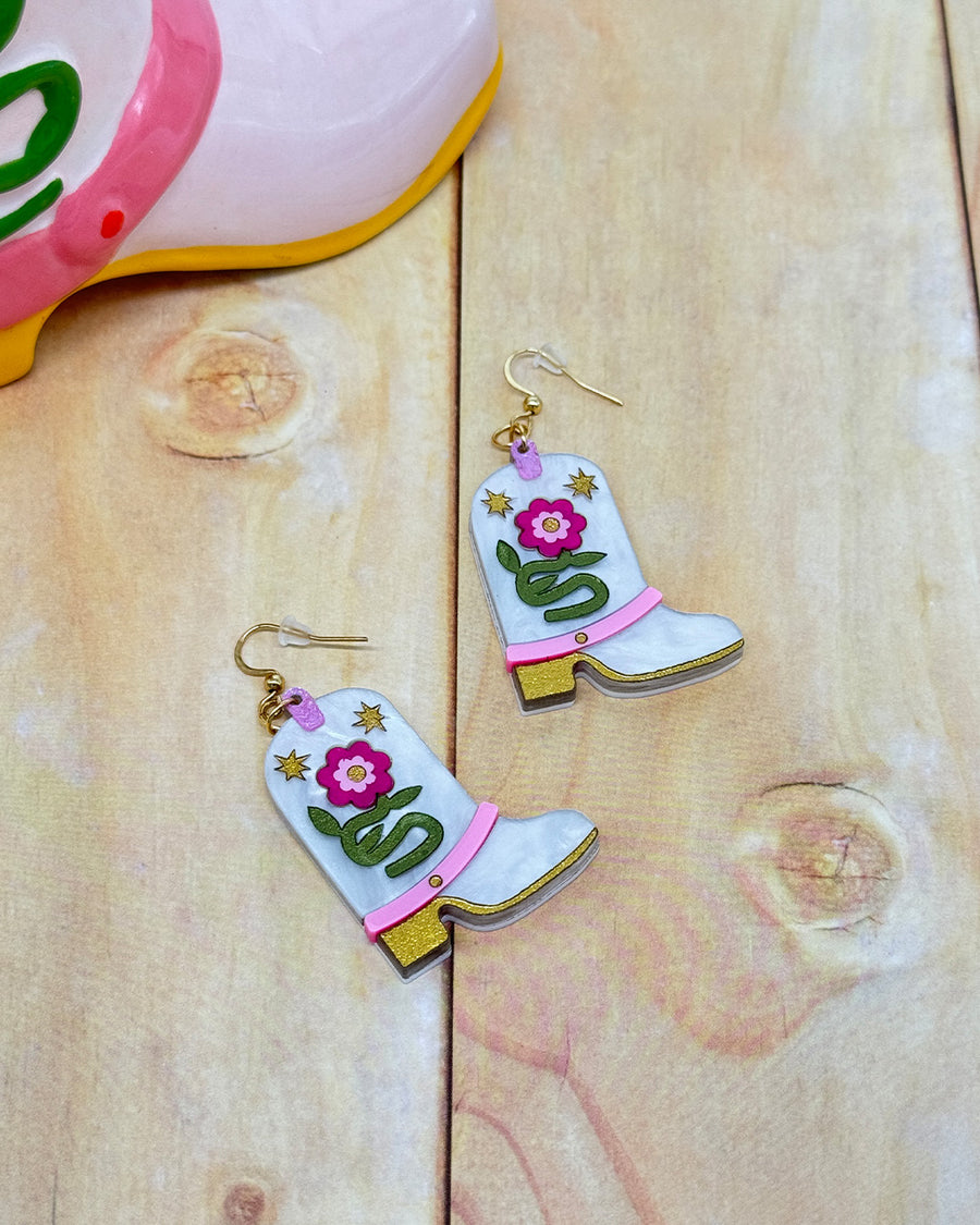 white pearl cowboy boot earrings with pink flowers and colorful glittery accents next to the giddy up vase