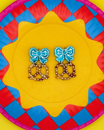 earrings with blue bow stud and pretzel dangle on colorful plate