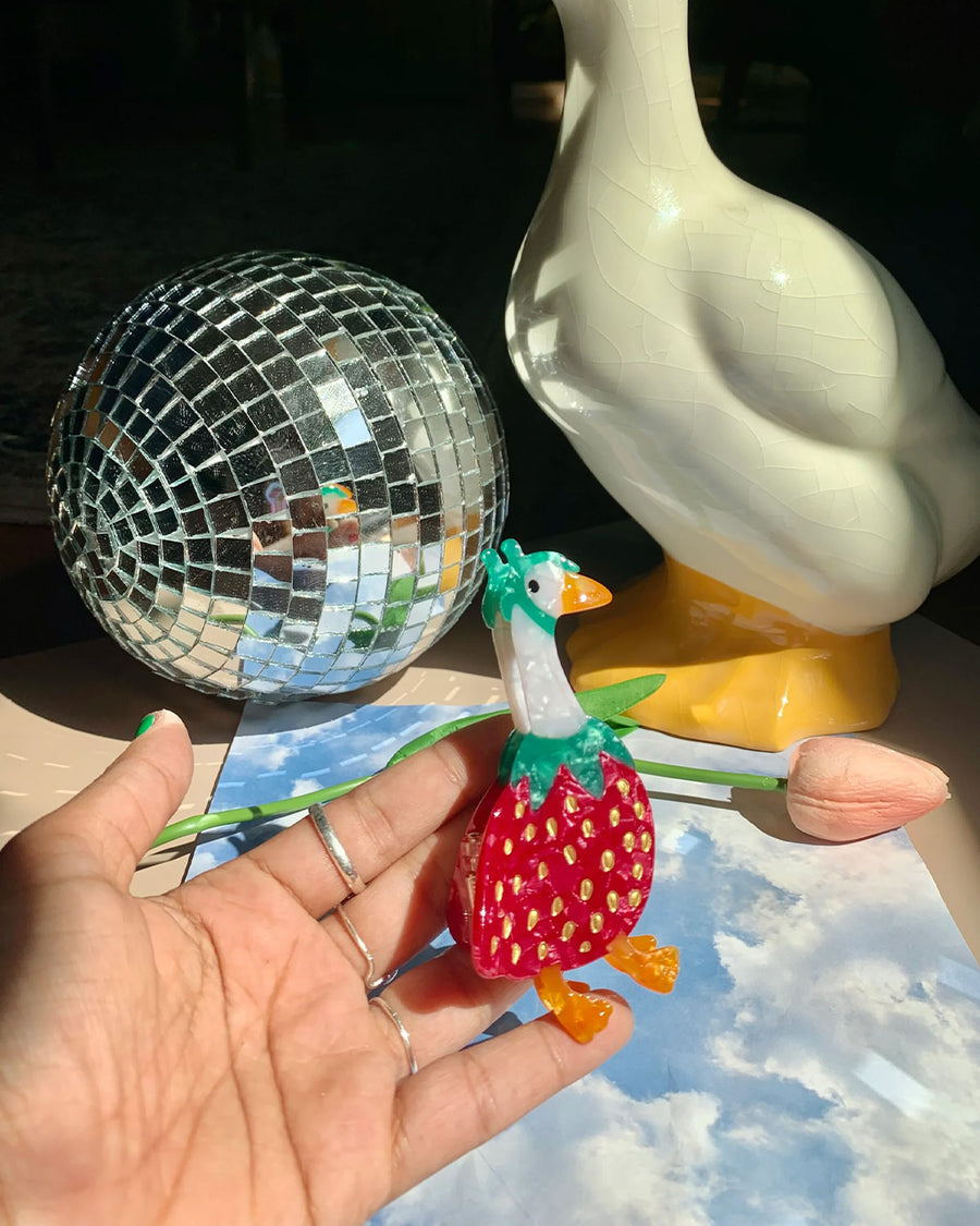 model holding hair claw with goose wearing a strawberry outfit