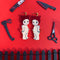 baby wearing devil horn hat and tail dangle earrings surrounded by knives, axe, and scissors