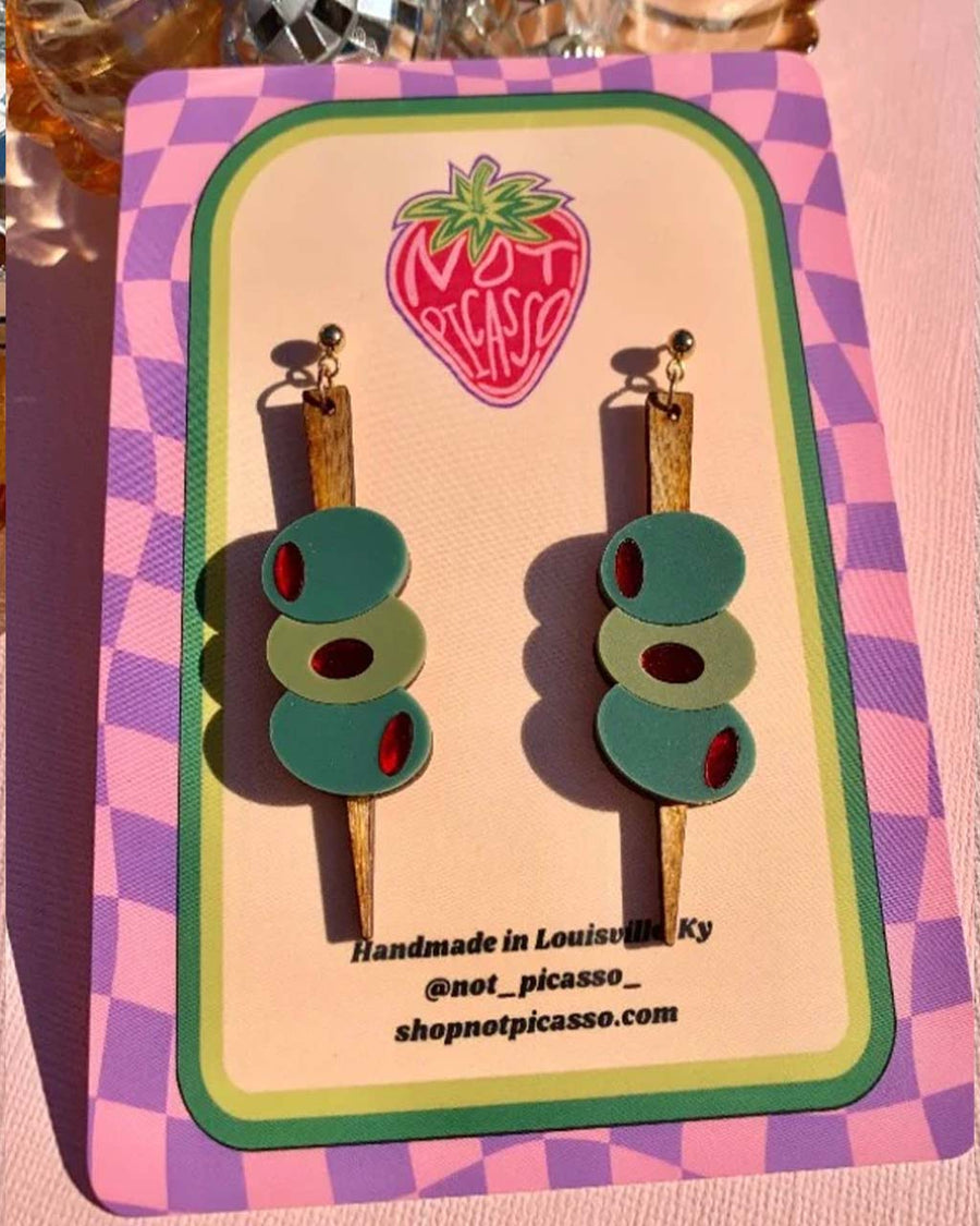 packaged pair of earrings with three green olives with a wooden stick through them