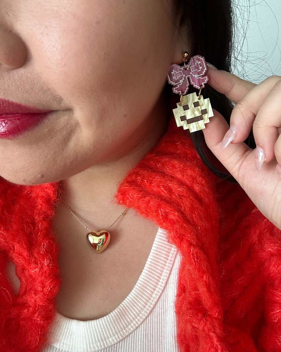 model wearing pink bow dangle earring with yellow smiley