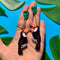 model holding toucan shaped dangle earrings with green leaf stud