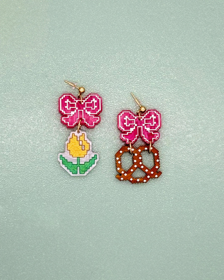 earrings with pink bow stud and one earring with a yellow tulip and one with a pretzel dangle