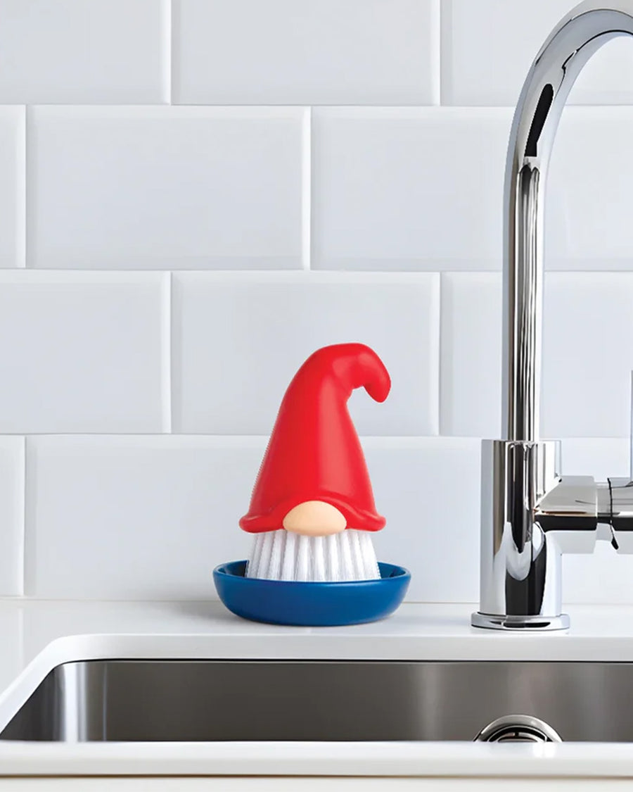 gnome dish brush with red hat and blue tray on a sink