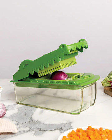 green crocodile shaped veggie chopper with an onion in it