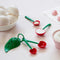 cherry shaped measuring spoons with various baking ingredients in them