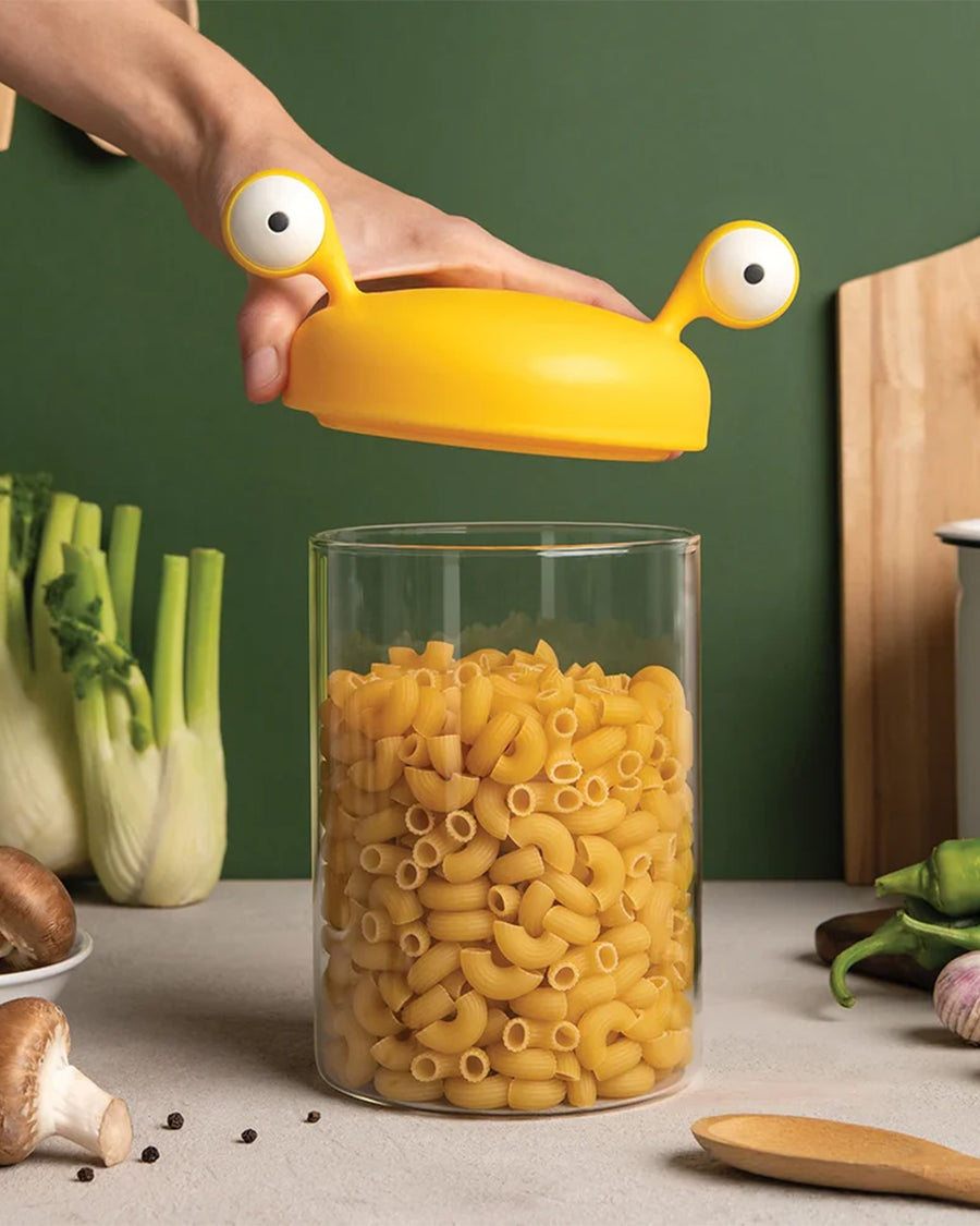 model pulling lid off of small yellow monster pasta holder