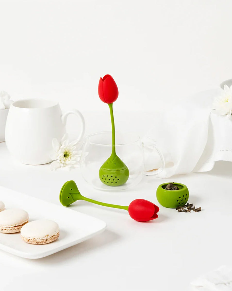 red tulip tea infuser with loose tea leaves next to it