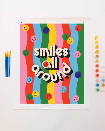 colorful paint by numbers kit with smiley and 'smiles all around' typography and comes with pots of paint and paintbrushes