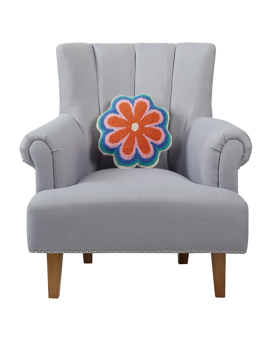 orange, pink, blue, and teal vibey flower shaped throw pillow on a chair