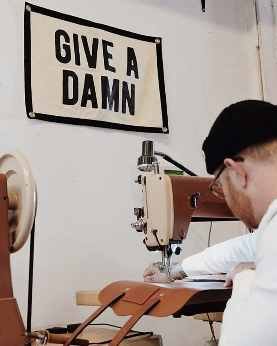 cream camp flag with black border and black 'give a damn' across the front hanging in a sewing room