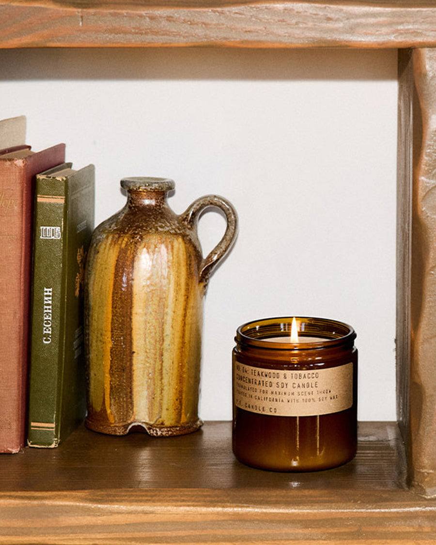 teakwood and tobacco large concentrated candle on a shelf with decor