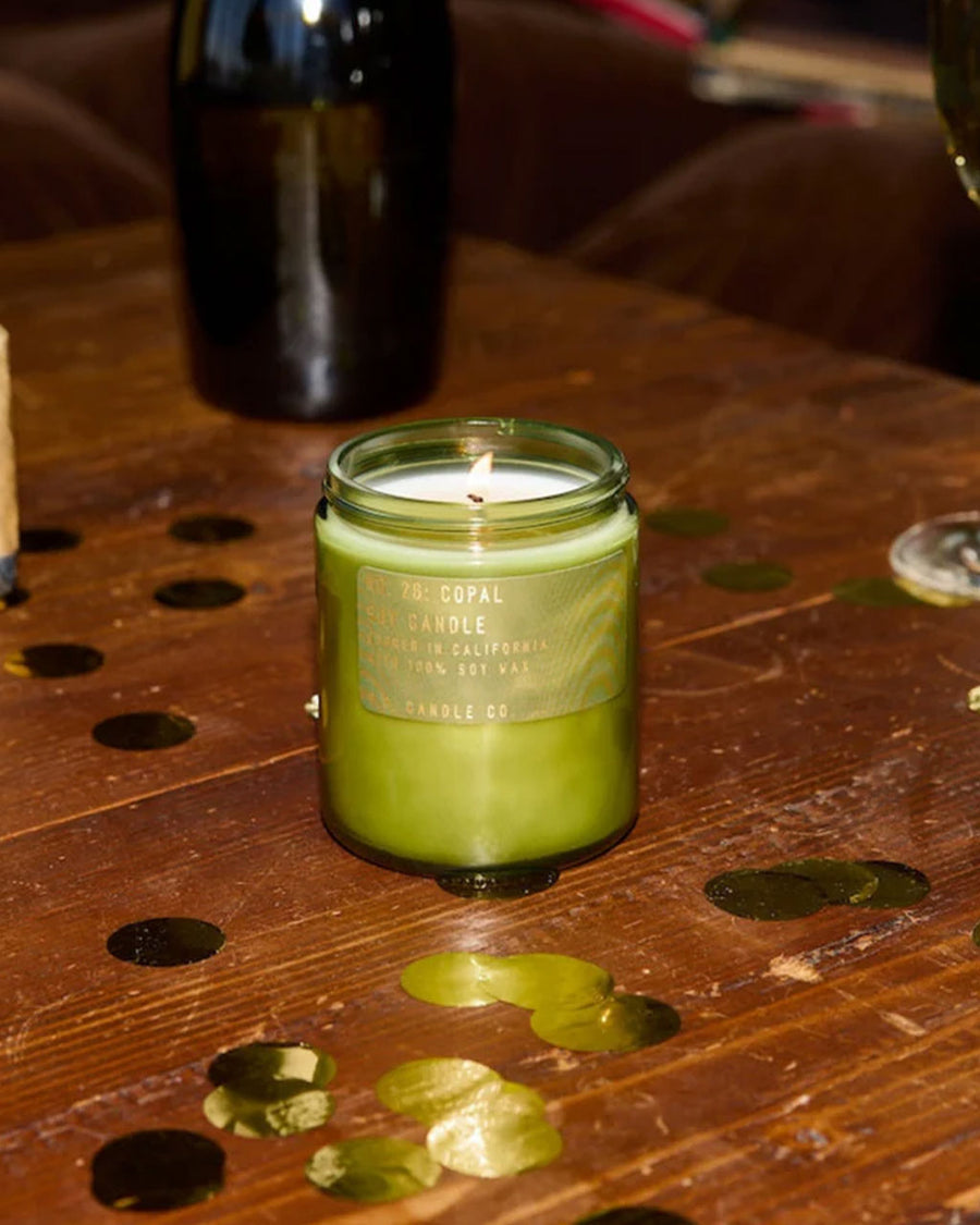 lit copal scented standard candle on a table with gold confetti