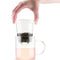 model pulling infuser out of 12 oz clear glass tea glass with removable infuser