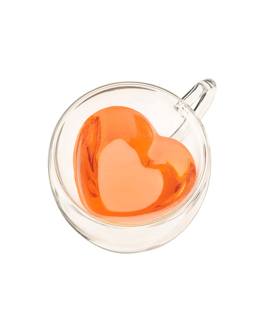 top view of heart shaped clear glass mug with peach liquid inside